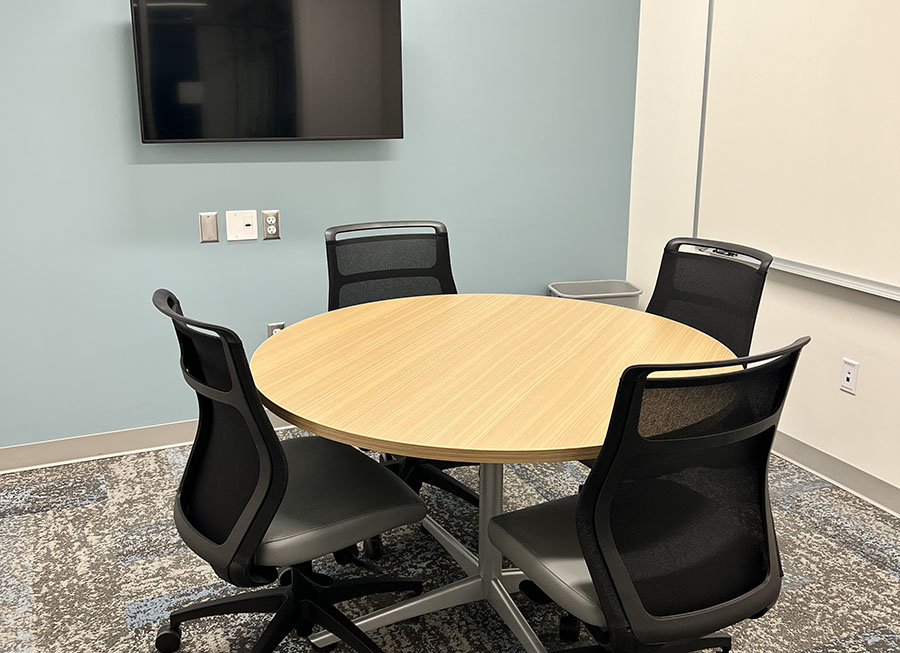 Study room with a table and chairs and a computer screen on the wall